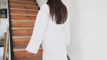 Young woman in robe walks up stairs video