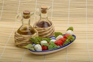 Caprese salad in a bowl on wooden background photo