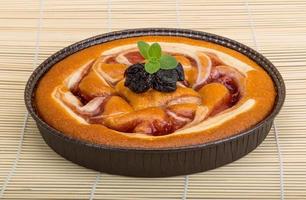 Plum cake in a bowl on wooden background photo