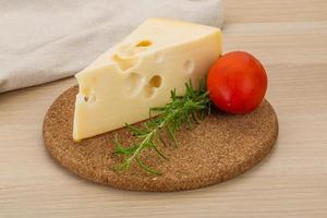 Cheese maasdam on wooden board and wooden background photo