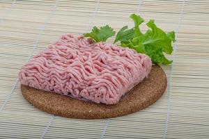 carne de cerdo picada cruda sobre tabla de madera y fondo de madera foto