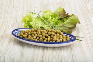 Marinated peas in a bowl on wooden background photo