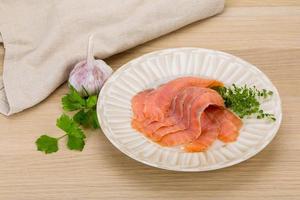 salmón en rodajas en el plato y fondo de madera foto