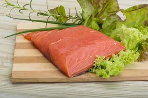 Salmon fillet on wooden board and wooden background photo