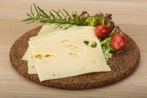 Maasdam cheese on wooden board and wooden background photo