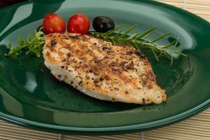 Grilled chichen breast on the plate and wooden background photo