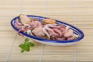 Seafood cocktail in a bowl on wooden background photo