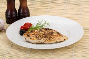 Grilled chichen breast on the plate and wooden background photo