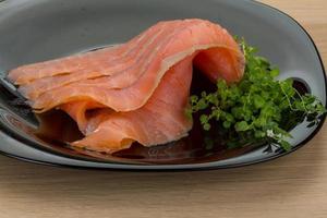 Sliced salmon on the plate and wooden background photo