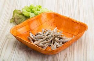 Dries anchovy in a bowl on wooden background photo