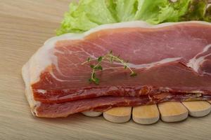 Prosciutto on wooden board and wooden background photo