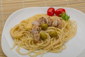 Spaghetti with chicken on the plate and wooden background photo