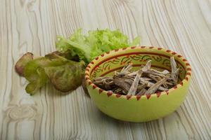 Dries anchovy in a bowl on wooden background photo