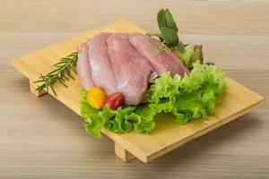 Raw pork schnitzel on wooden board and wooden background photo