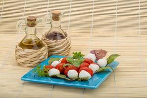Caprese salad on the plate and wooden background photo