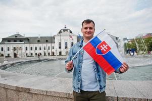 hombre que sostiene la bandera en el palacio grassalkovich, bratislava, europa. residencia del presidente de eslovaquia en bratislava. foto