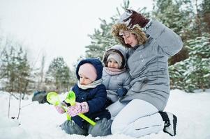 Mother with two baby girl daughters in winter nature. Outdoors in snow. photo