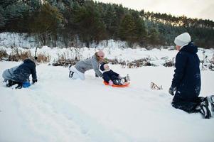 Mother playing with children in winter nature. Outdoors in snow. photo