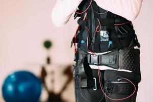 entrenamiento ems. chica haciendo ejercicios en un traje con cables. foto