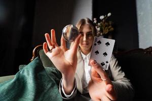 Woman in business suit holding crystal ball and six spade photo