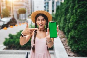 woman showing modern smartphone with green screen for replacement photo