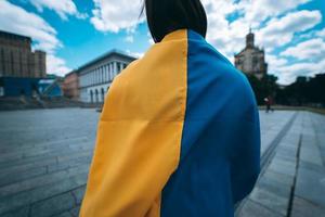 Back view. Young woman covered with the Ukrainian flag photo