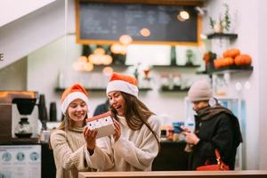 The girl gives a gift to her female friend in caffe photo