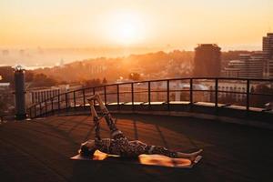 Woman doing yoga on the roof of a skyscraper in big city. photo