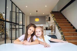 dos niñas en la mesa mirando el primer plano de la cámara foto