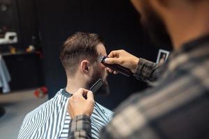 Master in barbershop makes men's haircutting with hair clipper photo