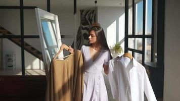 mujer joven en vestido de verano revisa la ropa en el espejo video