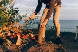 Man chops wood with a large bonfire knife on a sunny day. photo