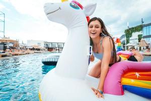 mujer joven feliz sentada en un colchón inflable de juguete de unicornio foto