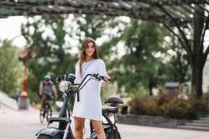 Young beautiful woman and an electric scooter, ecological transport photo