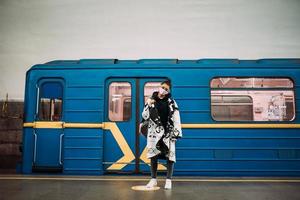 mujer joven de pie en la estación con máscara de protección médica foto