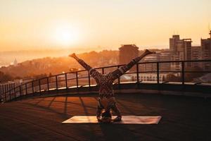 Woman doing yoga on the roof of a skyscraper in big city. photo