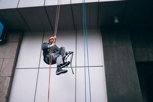 Industrial climber in uniform and helmet rises photo