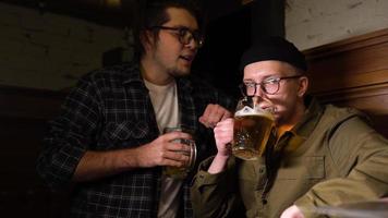 jóvenes amigos divirtiéndose juntos bebiendo cerveza y tintineando vasos en un pub. foto