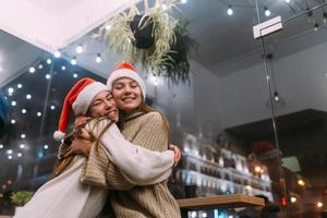 Portrait of happy cute young friends hugging each other at caffe. photo