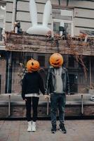 un chico y una chica con cabezas de calabaza. pareja tomados de la mano foto