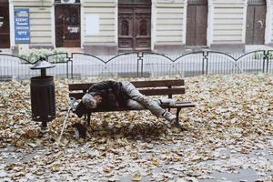 personas sin hogar durmiendo en los bancos en el parque de otoño foto