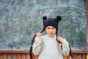 Little girl in a hat posing on the background of the school blackboard photo