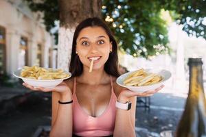 Young women hold french fries on white plates. Street cafe photo