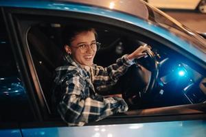 mujer conduciendo un coche por la noche en la ciudad foto