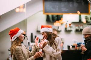 The girl gives a gift to her female friend in caffe photo