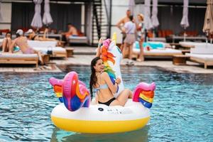 Woman on inflatable unicorn toy mattress float in pool. photo