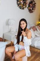 Brunette combs her hair with a comb while sitting in the bedroom photo