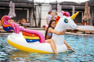 Woman on inflatable unicorn toy mattress float in pool. photo