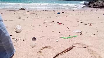 en kvinna promenader barfota på en strand full av sopor, torr kvistar och strö med plast. problem av spillts skräp skräp sopor på de strand sand orsakade förbi konstgjorda. miljö- och ekologi begrepp video