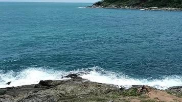 vue aérienne des vagues de l'océan frappant les falaises rocheuses dans l'océan bleu. vue de dessus des rochers côtiers dans l'océan de phuket. point de vue paysage du cap laem phromthep le matin. video